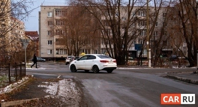 В одном городе, на дороге, автомобиль делает маневр поворота, уступая дорогу пешеходу.